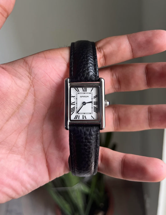 Black wristwatch with a silver case on a person's wrist against a neutral background. Sanda 1108 black leather strap