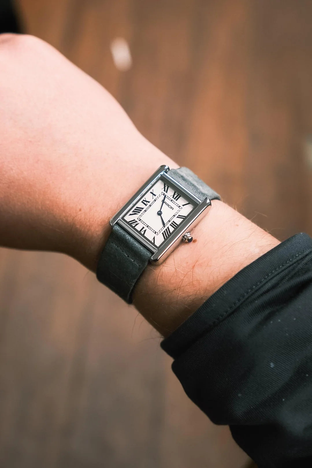 Person wearing a black wristwatch with a blurred background